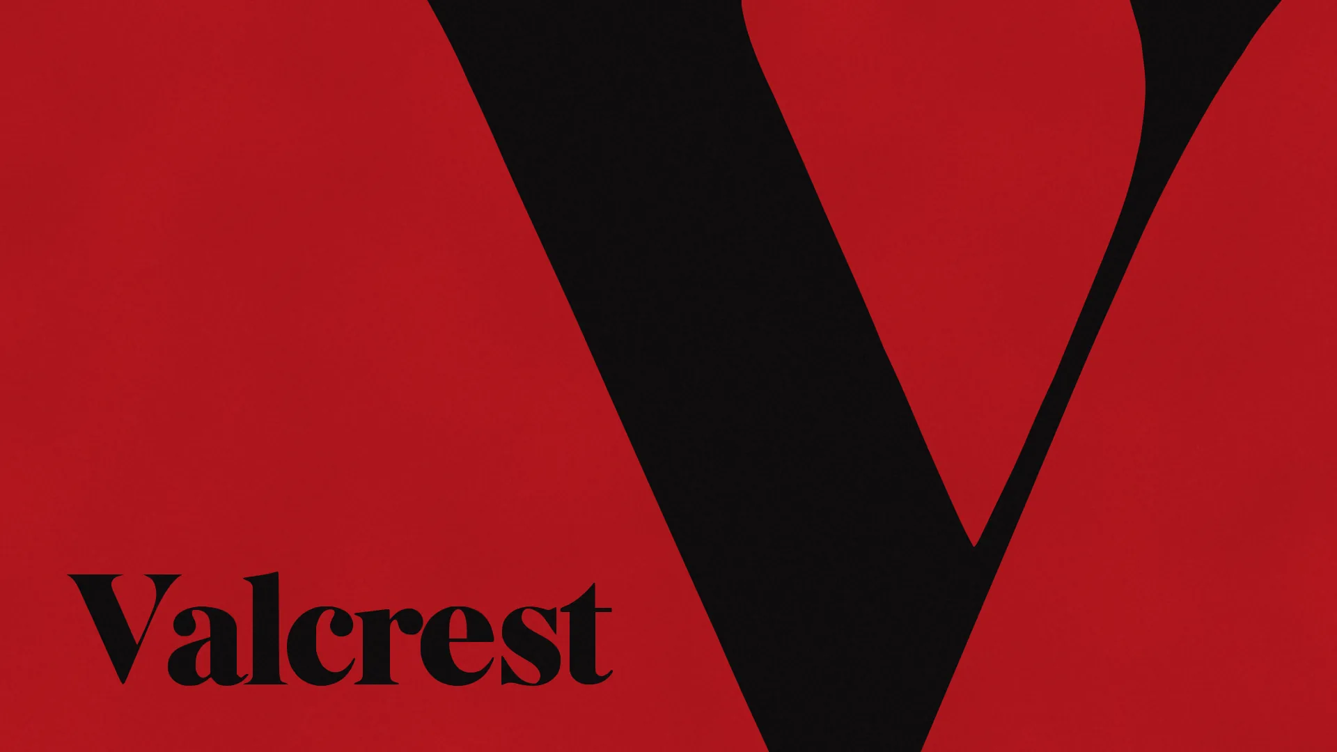 A giant black capital V of VALCREST, cropped by the top and bottom of the frame, on red, with the name Valcrest in black at the lower left.